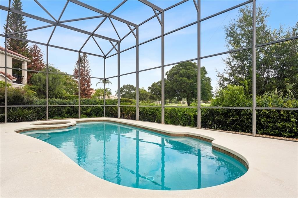 A swimming pool with a spa is enclosed by a screened lanai overlooking a backyard — 1240 GLENCREST DRIVE, LAKE MARY, FL
