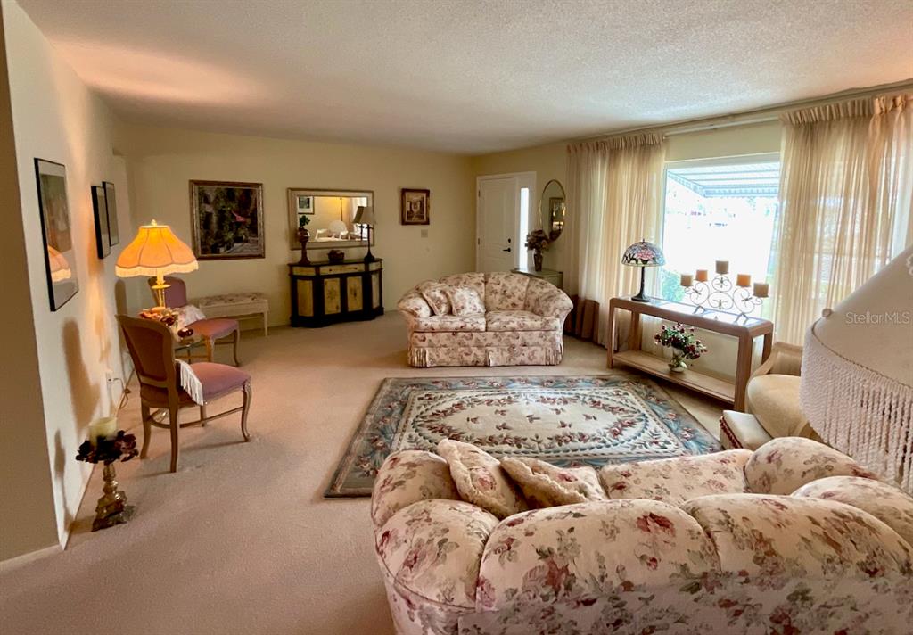 A living room features floral sofas, a patterned area rug, and a large window — 3807 99TH TERRACE N, PINELLAS PARK, FL