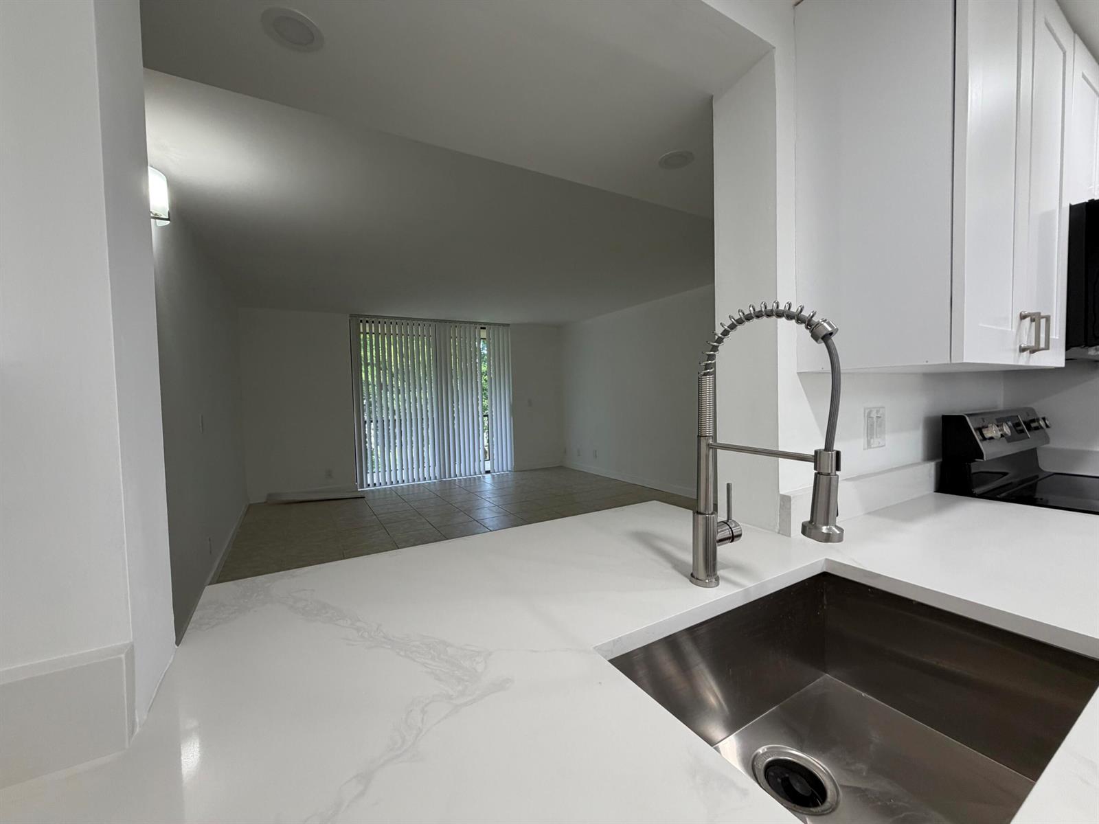 A kitchen with white cabinets, quartz countertops, stainless steel appliances, and a pass-through window — 5220 Las Verdes Circle # 317, Delray Beach FL 33484, DELRAY BEACH, FL