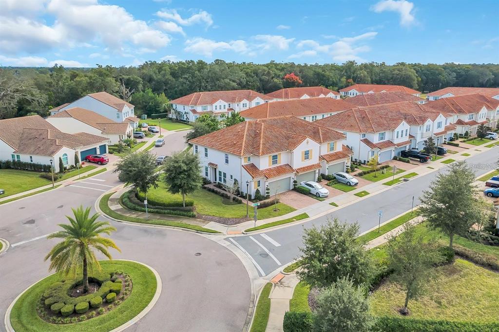 An aerial view shows a suburban neighborhood with multi-story townhomes, paved streets, and landscaped lawns — 2795 BOLZANO DRIVE, APOPKA, FL