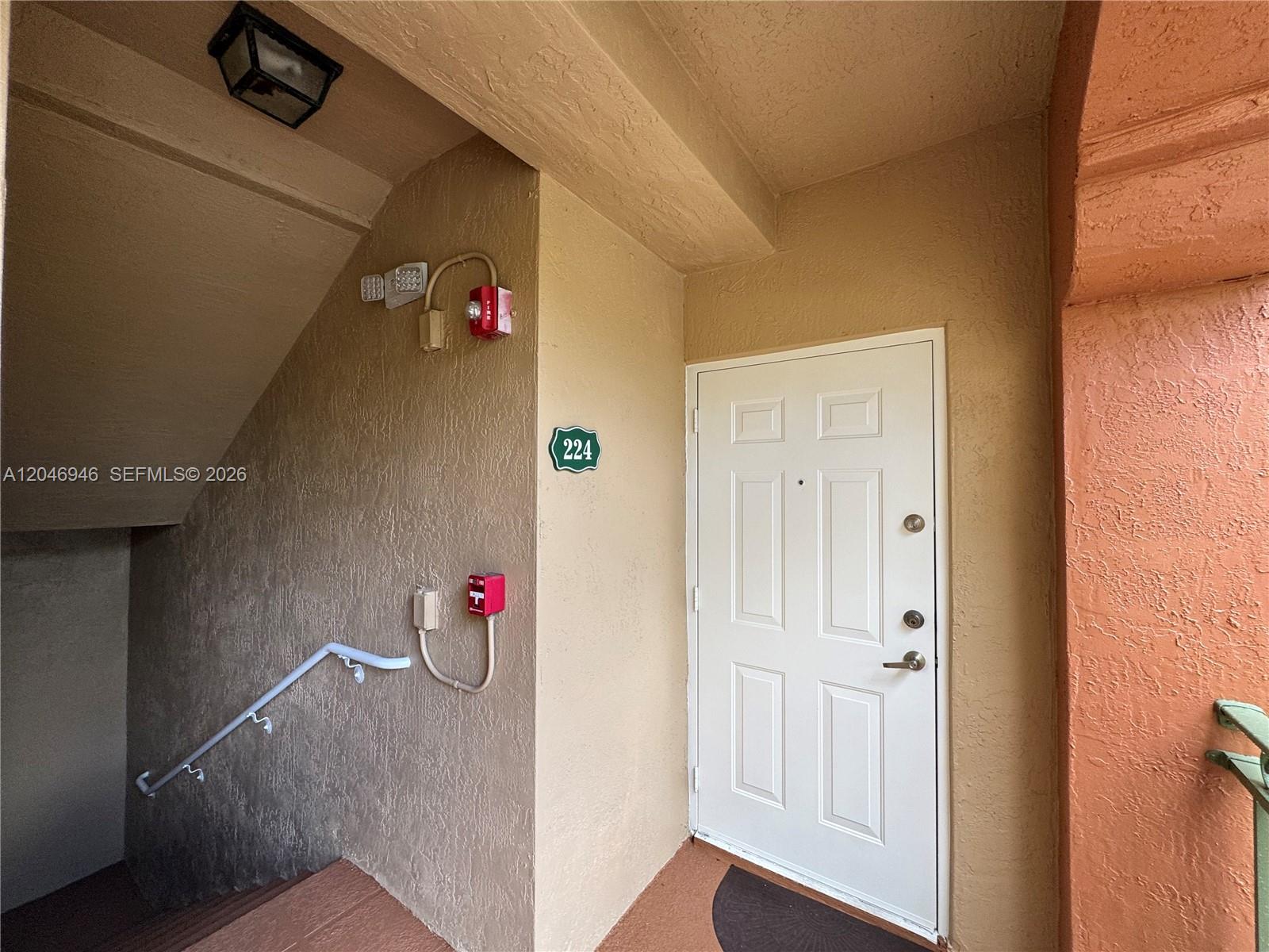A white door with the number 224 is located next to a stairwell and fire alarm — 6360 NW 114th Ave # 224, Doral FL 33178, DORAL, FL