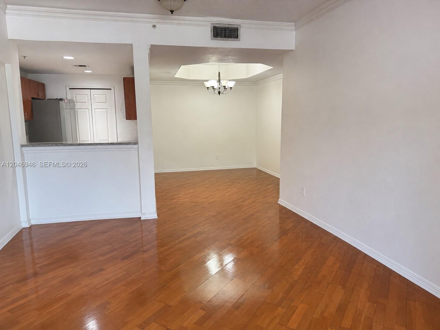 An open-concept living area features hardwood floors, a dining space with a chandelier, and kitchen — 6360 NW 114th Ave # 224, Doral FL 33178, DORAL, FL