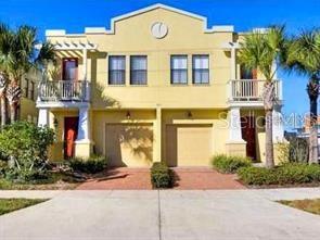 A two-story yellow townhouse with two garages, balconies, and palm trees under a blue sky — 107 S PACKWOOD AVENUE UNIT D, TAMPA, FL