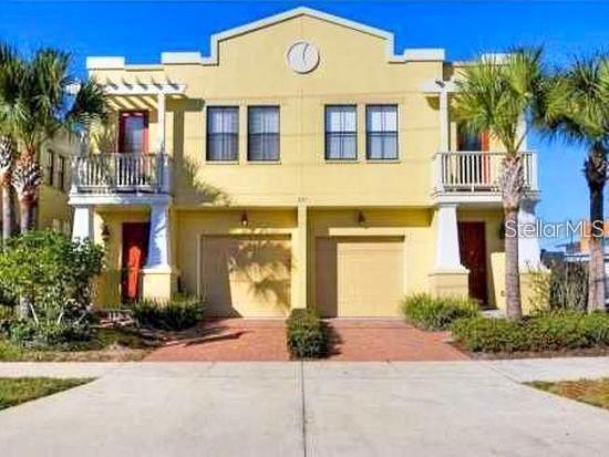 A two-story yellow townhouse with two garages, balconies, and palm trees under a blue sky — 107 S PACKWOOD AVENUE UNIT D, TAMPA, FL