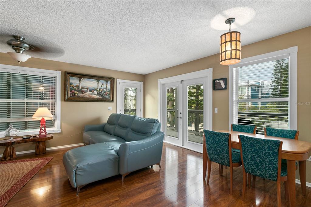 A living and dining area features hardwood floors, a blue sectional, and glass patio doors — 2511 AVENUE C UNIT West, BRADENTON BEACH, FL