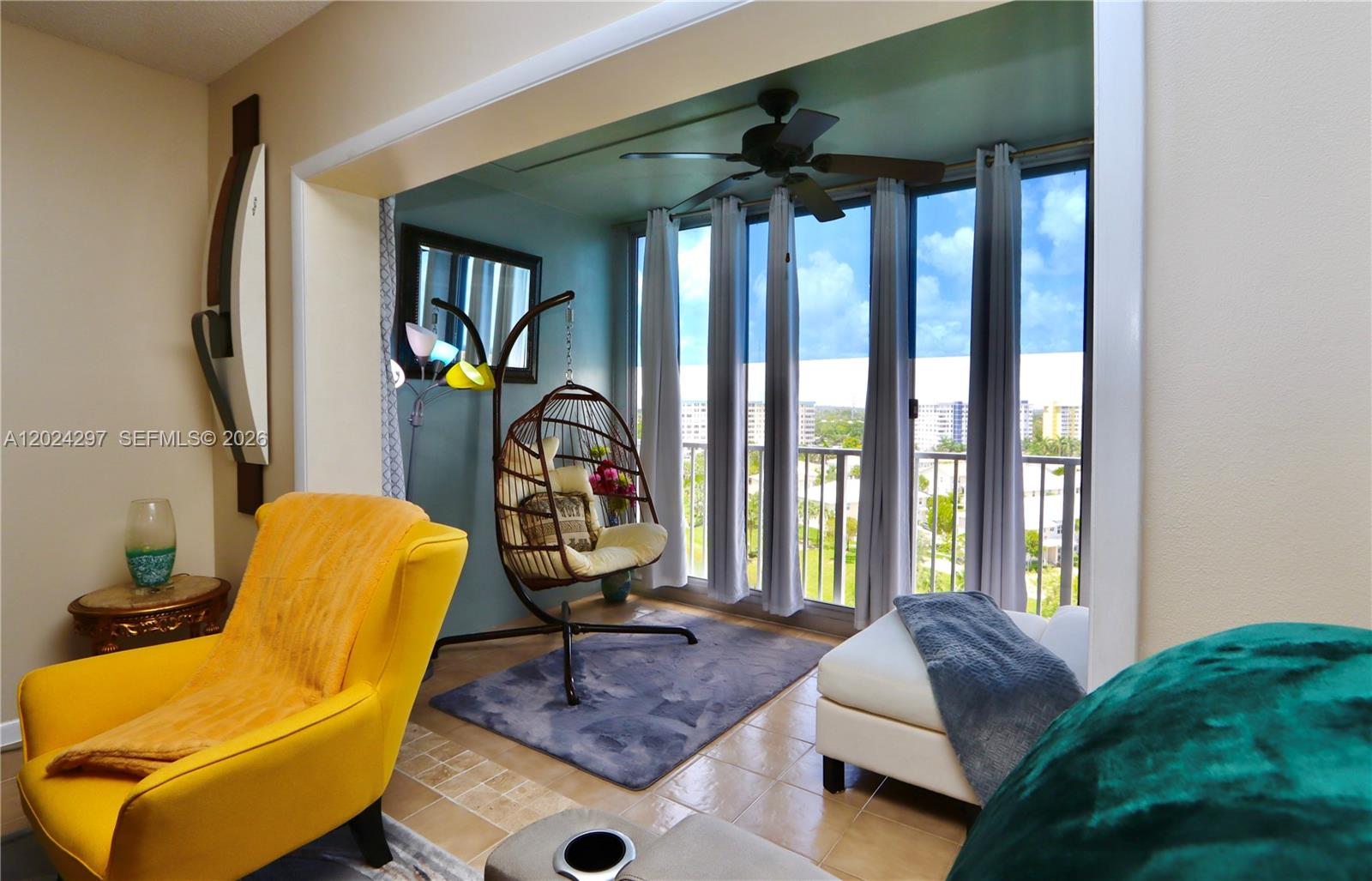 A sunroom features a hanging chair, tile flooring, and floor-to-ceiling windows with a balcony view — 3850 Washington St # 1010, Hollywood FL 33021, HOLLYWOOD, FL