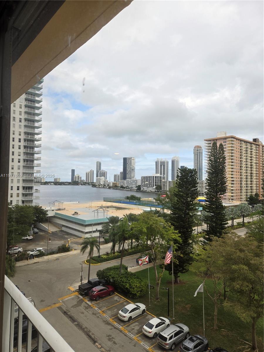 A high-angle view shows a waterfront city skyline with high-rise buildings and a parking lot — SUNNY ISLES BEACH, FL