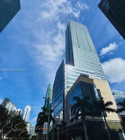 A low-angle view of a modern glass skyscraper under a bright blue sky — 1435 Brickell Ave # 3508, Miami FL 33131, MIAMI, FL
