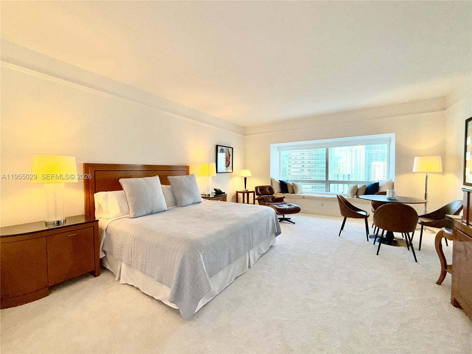 A bedroom features a king bed, a seating area with a table, and large windows — 1435 Brickell Ave # 3508, Miami FL 33131, MIAMI, FL