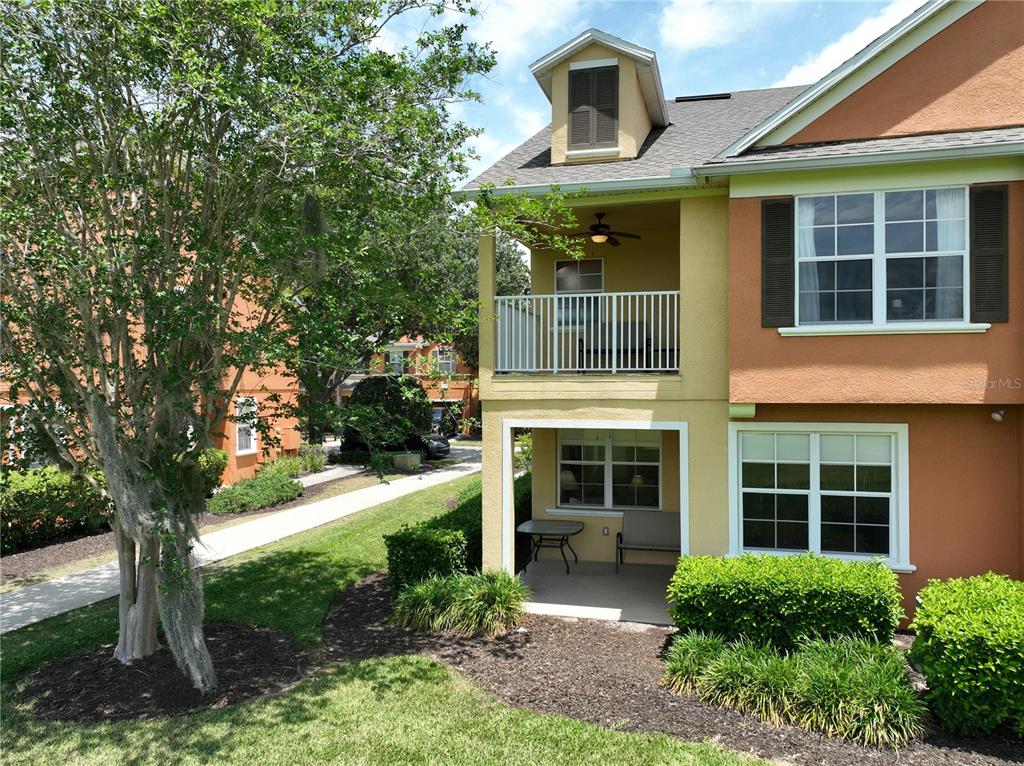 A two-story building exterior features a covered ground-floor patio and an upper-level balcony — 7586 ASSEMBLY LANE, REUNION, FL