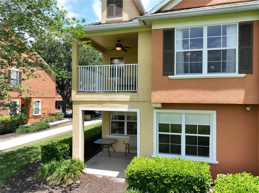 A two-story building exterior features a ground-level patio and an upper-level balcony with a fan — 7586 ASSEMBLY LANE, REUNION, FL