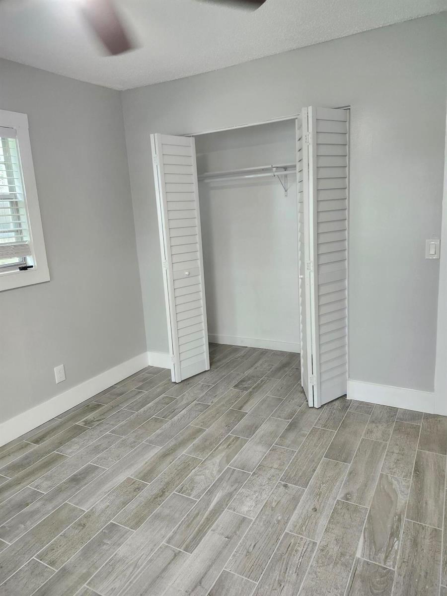 A bedroom with gray walls, wood-look tile flooring, and a white louvered closet door — 272 Tilford M, Deerfield Beach FL 33442, DEERFIELD BEACH, FL