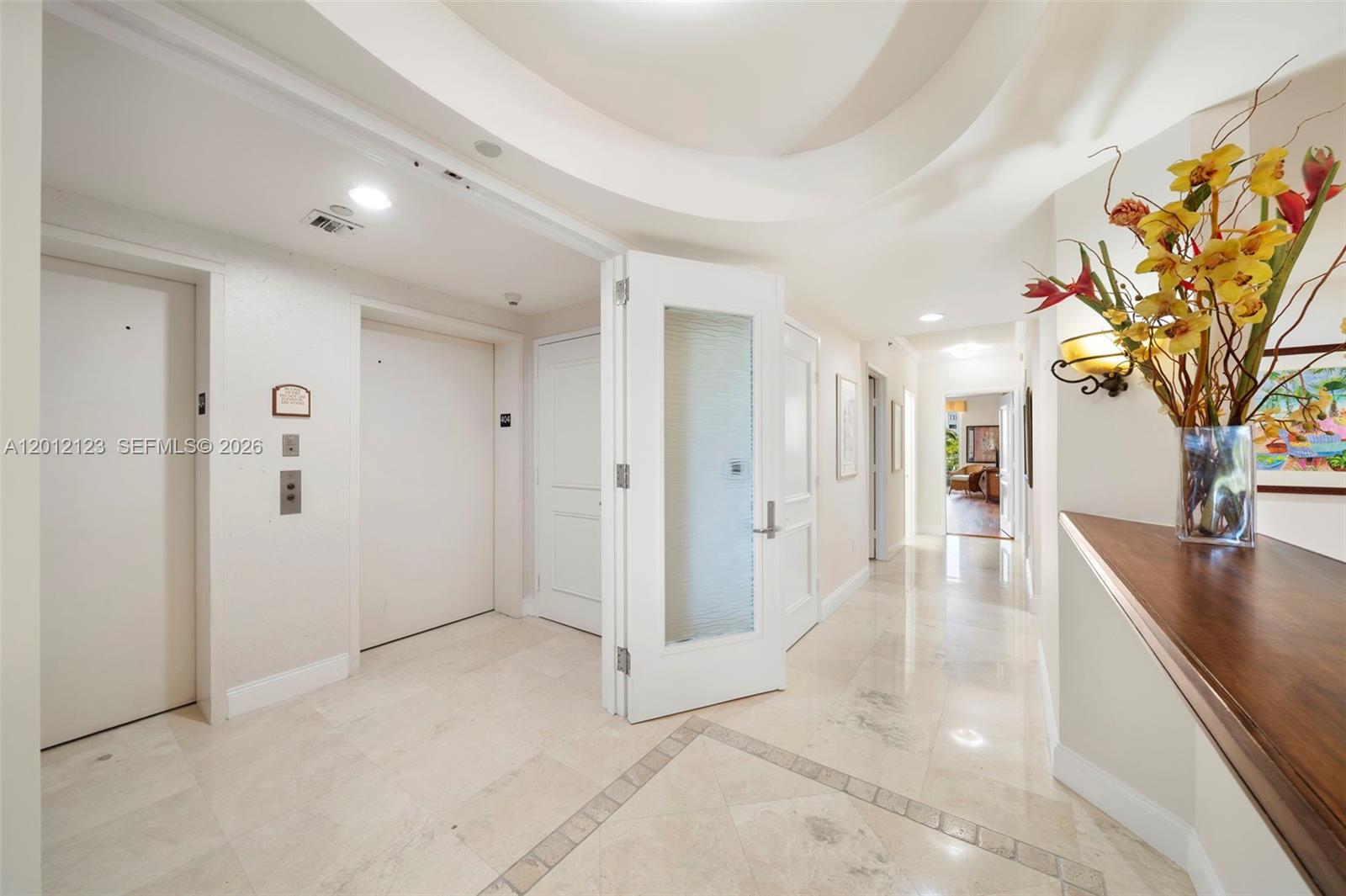 A bright hallway features marble tile flooring, a glass-paneled door, and an elevator entrance — 791 Crandon Blvd # 404, Key Biscayne FL 33149, KEY BISCAYNE, FL
