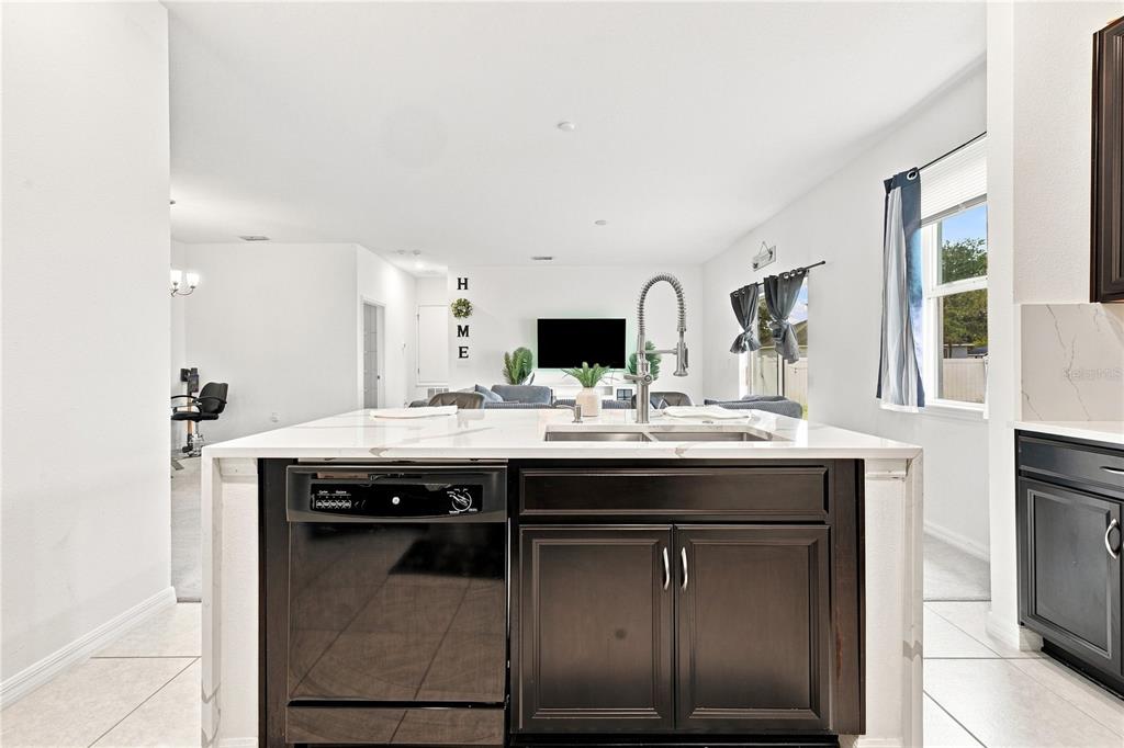 A kitchen island with a dark cabinet base and white countertop faces an open living area — 1045 DUDLEY DRIVE, KISSIMMEE, FL