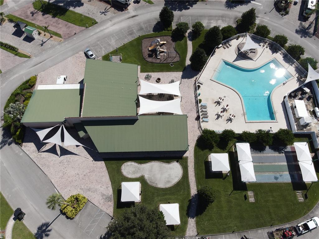 An aerial view shows a community center with a pool, playground, and outdoor recreational areas — 16409 BAY STREET UNIT 116, CLERMONT, FL