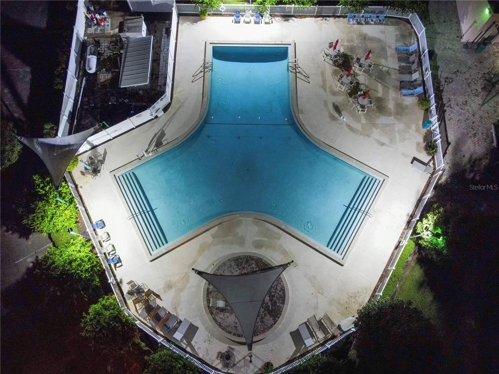 An aerial night view shows a tri-wing swimming pool surrounded by a patio and landscaping — 16409 BAY STREET UNIT 116, CLERMONT, FL