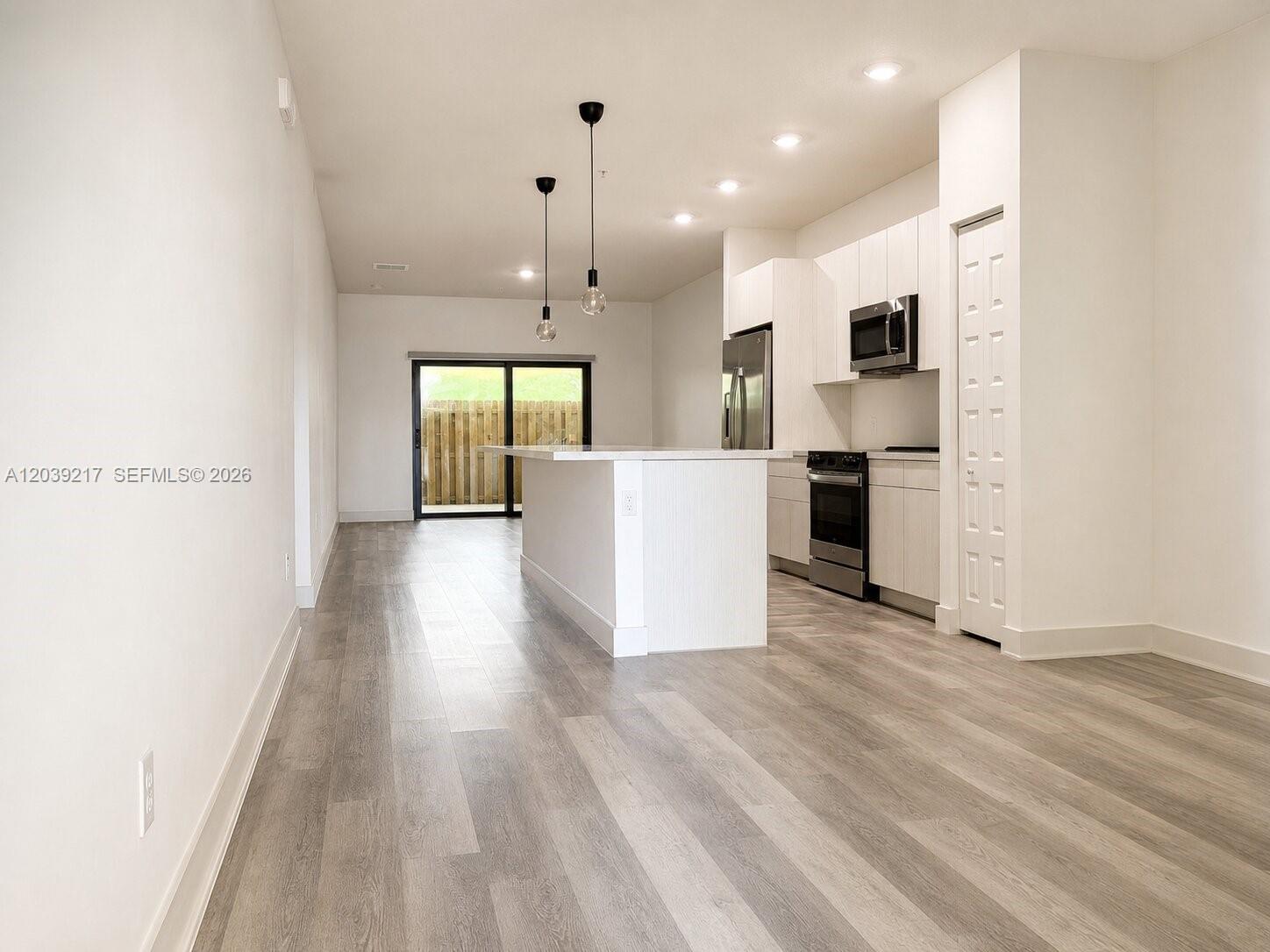 A modern kitchen features white cabinetry, stainless steel appliances, and an island with pendant lighting — 7809 NW 104th Ave # 5, Doral FL 33178, DORAL, FL