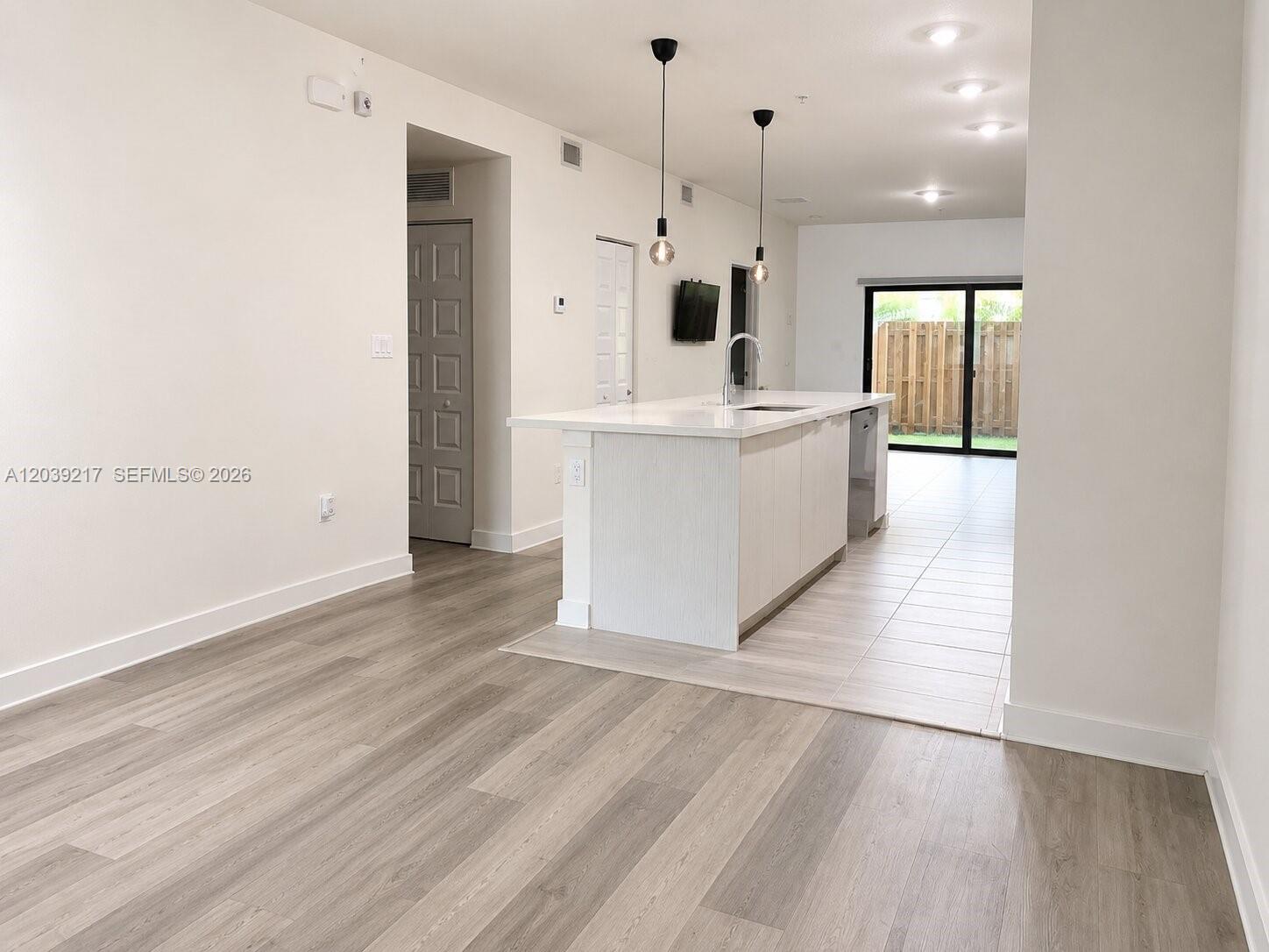 A kitchen with a white island and light wood flooring opens to a patio area — 7809 NW 104th Ave # 5, Doral FL 33178, DORAL, FL