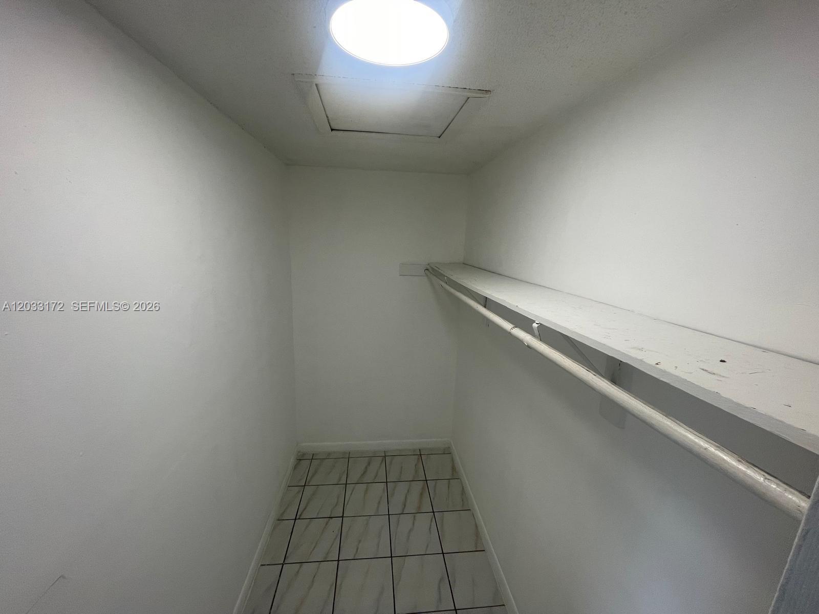 A small walk-in closet features white walls, tiled flooring, and a single shelf with a rod — 1717 NW 16th St # B, Miami FL 33125, MIAMI, FL