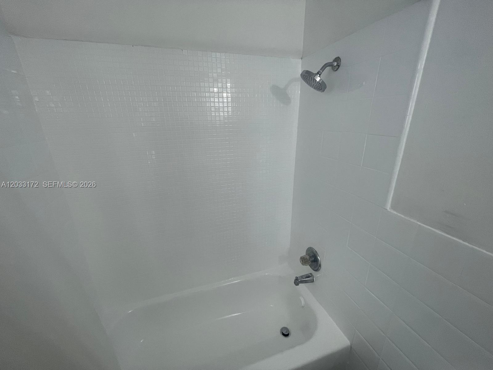 A white bathtub with a showerhead and tiled walls in a bathroom — 1717 NW 16th St # B, Miami FL 33125, MIAMI, FL