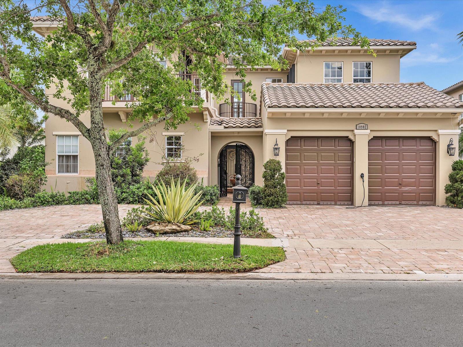 A two-story stucco house features a tile roof, two garage doors, and a paved driveway — 10982 NW 81st Manor, Parkland FL 33076, PARKLAND, FL