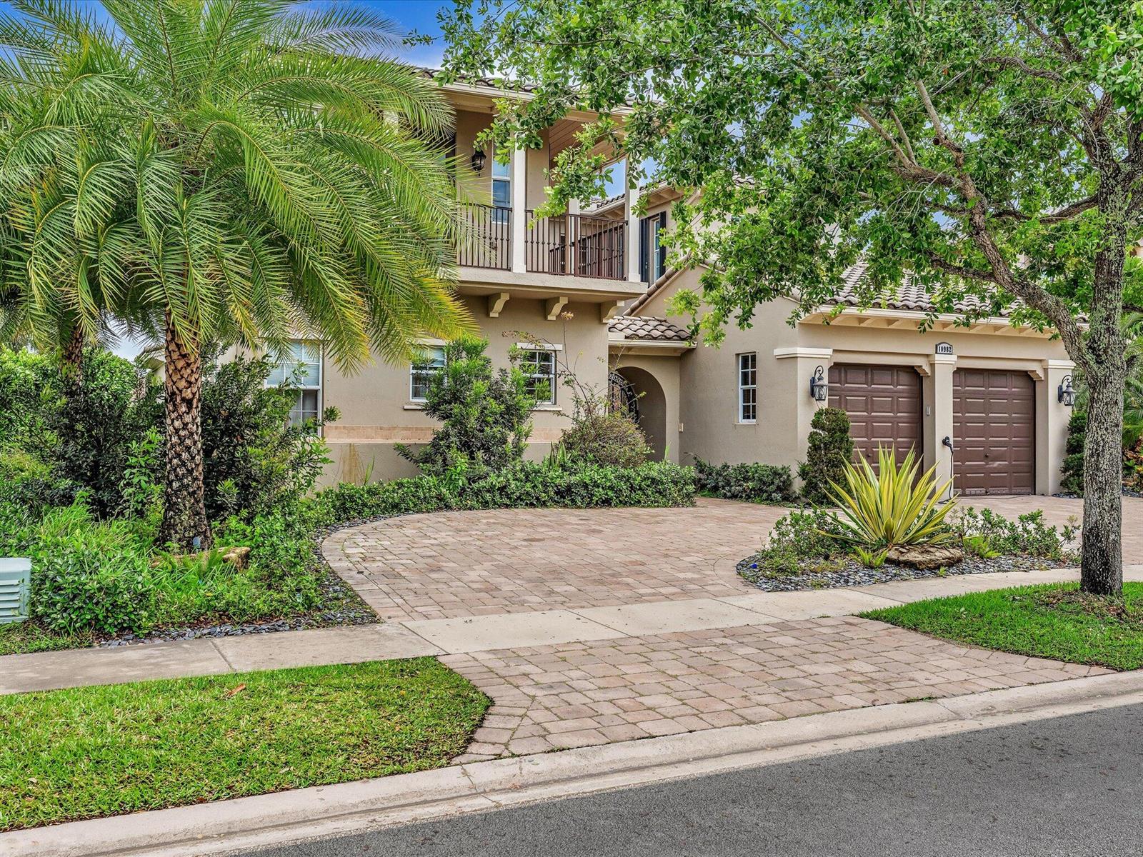 A two-story stucco house with a paver driveway, two-car garage, and a palm tree — 10982 NW 81st Manor, Parkland FL 33076, PARKLAND, FL