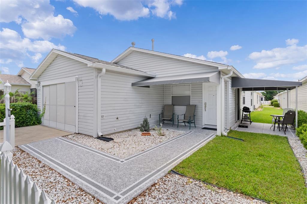A light gray house with a garage, a covered entryway, and a landscaped front yard — 16933 SE 94TH SUNNYBROOK CIRCLE, THE VILLAGES, FL