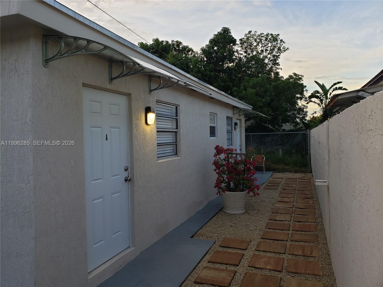 The exterior of a stucco building features a white door, a small window, and a walkway — 2481 SW 11 st, Miami FL 33135, MIAMI, FL