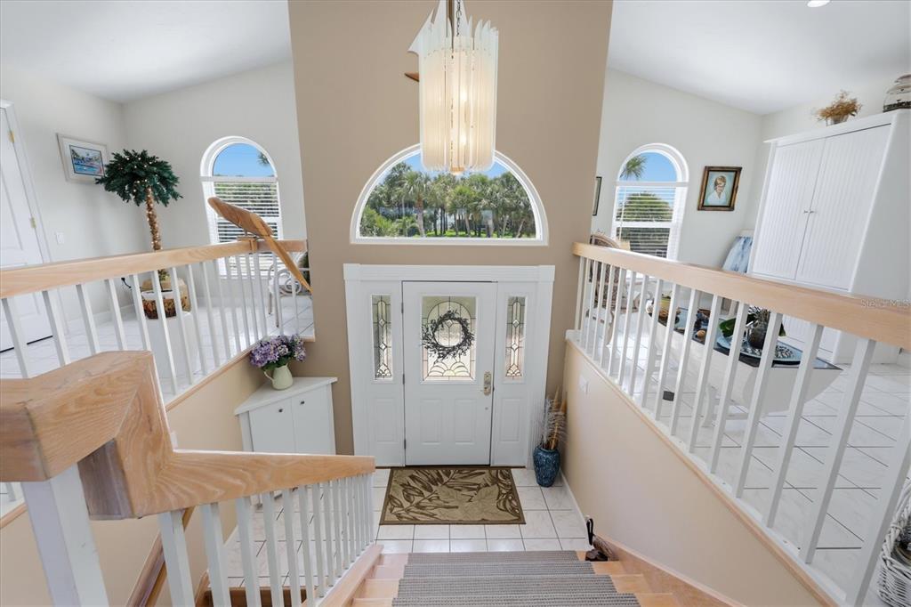 A staircase leads down to a white front door with a glass insert and arched window — 721 N MANASOTA KEY ROAD, ENGLEWOOD, FL