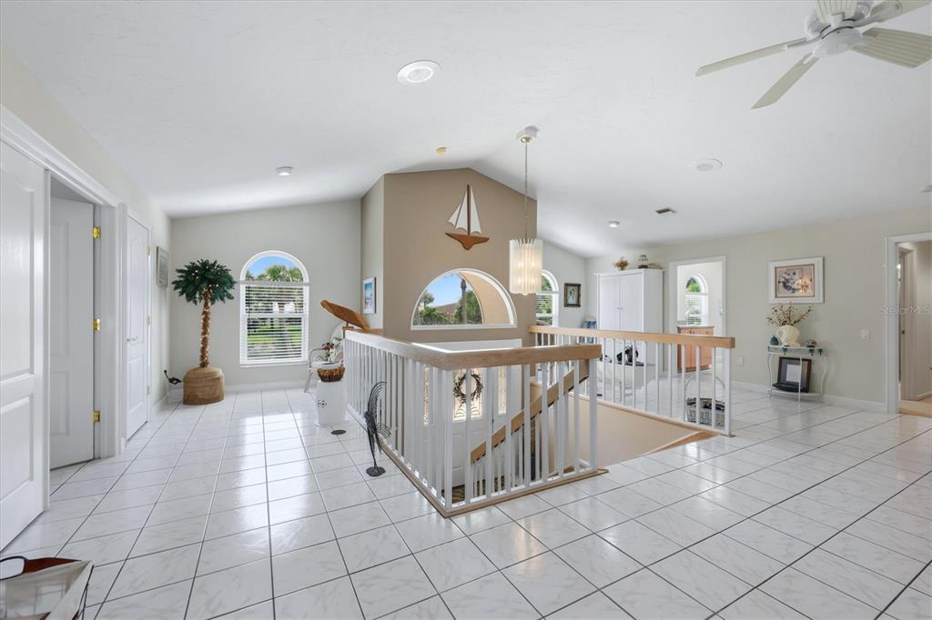 A bright, tiled landing features a staircase with white railings and a decorative sailboat wall ornament — 721 N MANASOTA KEY ROAD, ENGLEWOOD, FL