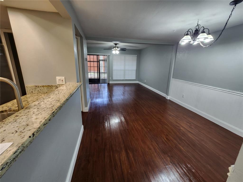 A dining area with dark wood floors, a chandelier, and a granite-topped kitchen counter — 823 SW 58TH TERRACE, GAINESVILLE, FL