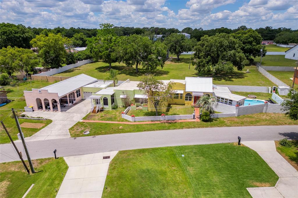 An aerial view shows a long, light-colored house with a pool and large backyard — 815 LAKE JESSIE DRIVE, WINTER HAVEN, FL