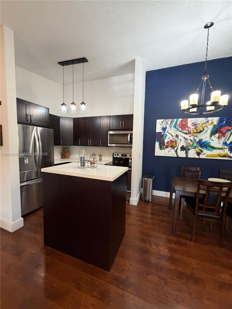 A kitchen with dark cabinets and a central island sits next to a dining area — 4944 NW 102nd Ave # 3, Doral FL 33178, DORAL, FL