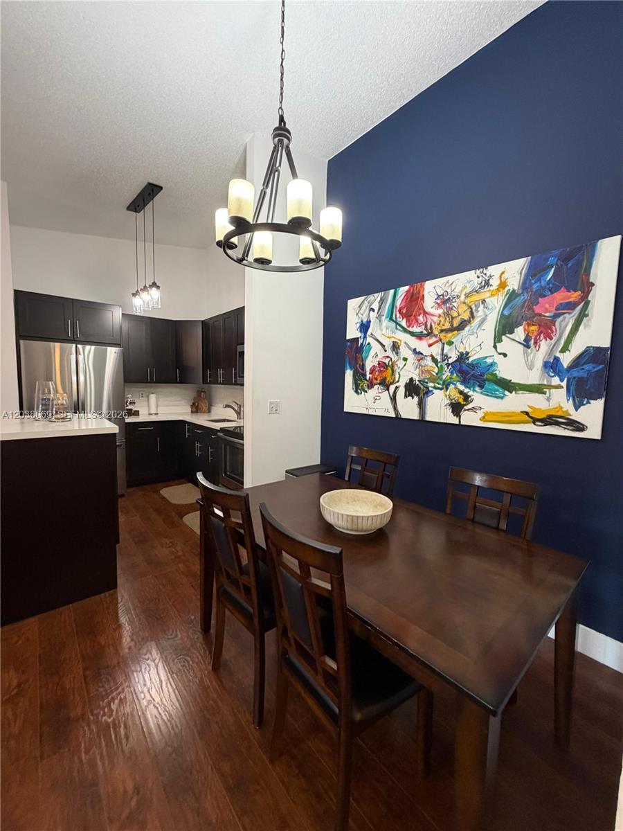 A dining area features a dark wood table, chairs, and a large abstract wall painting — 4944 NW 102nd Ave # 3, Doral FL 33178, DORAL, FL