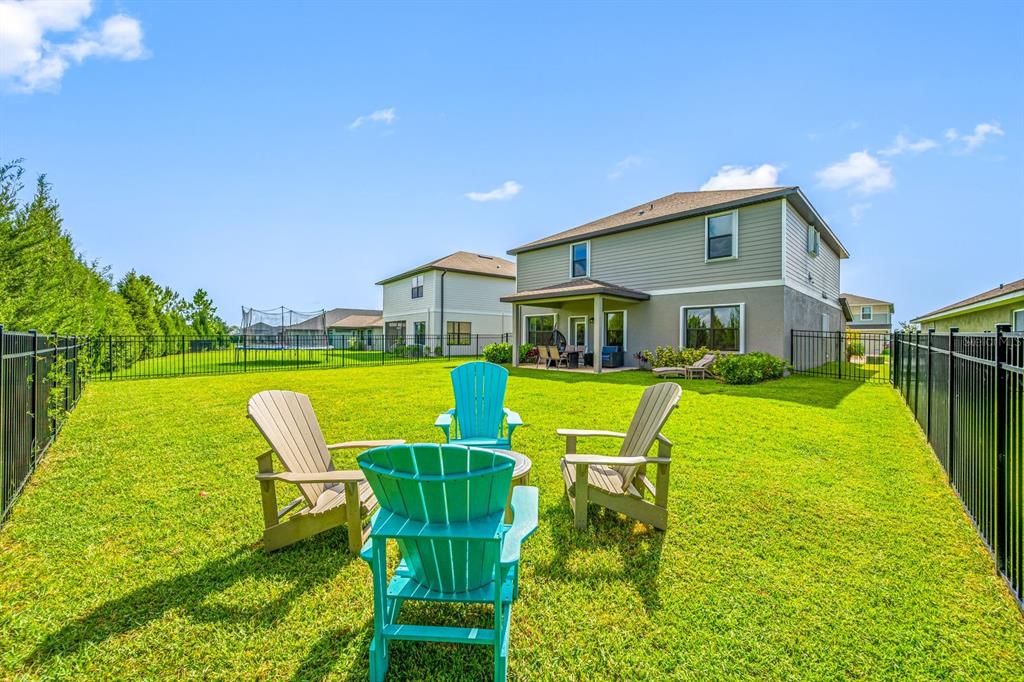 A backyard with a lawn, a black metal fence, and four Adirondack chairs — 6107 164TH AVENUE E, PARRISH, FL
