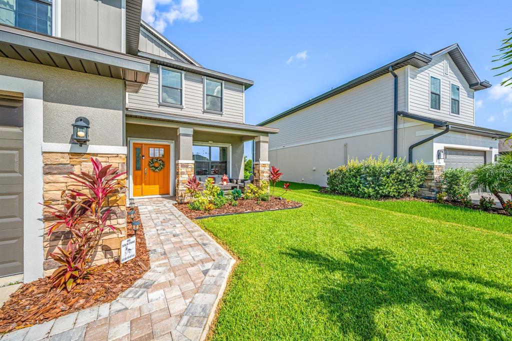A two-story house with a stone facade, orange front door, and a paved walkway — 6107 164TH AVENUE E, PARRISH, FL