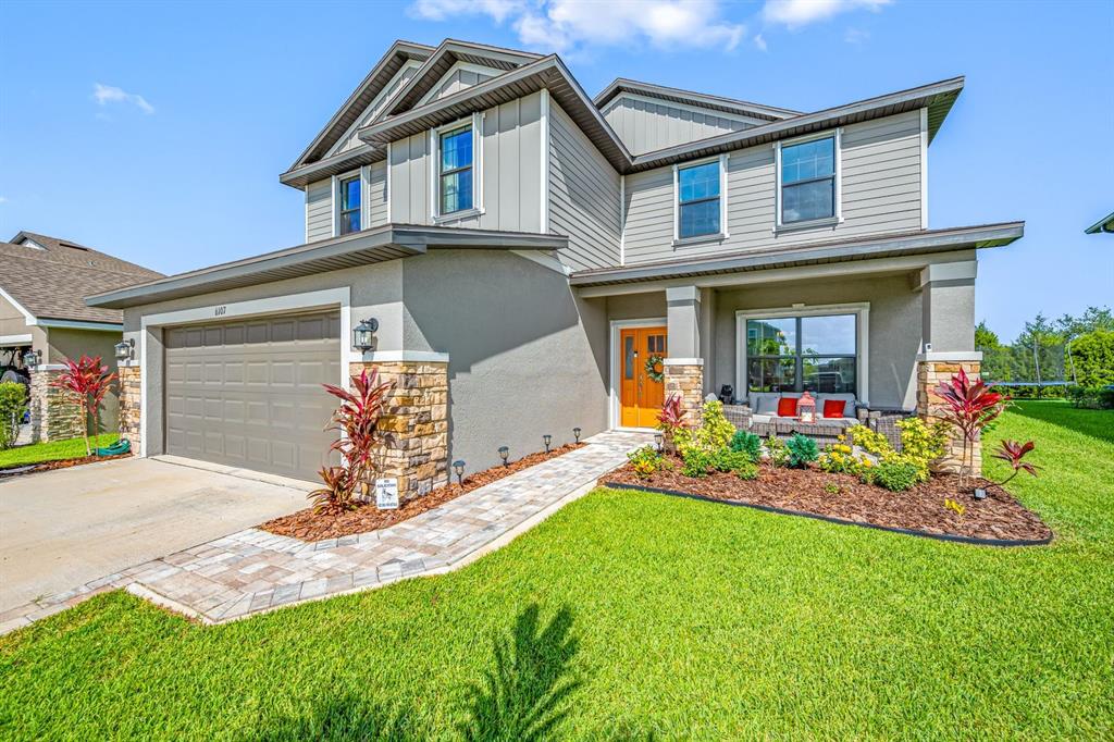 A two-story house with a gray exterior, stone accents, a garage, and a front porch — 6107 164TH AVENUE E, PARRISH, FL