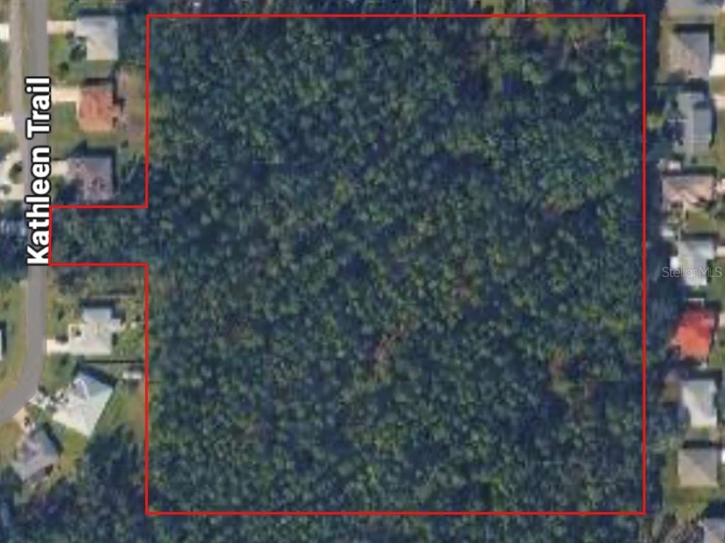 An aerial view shows a large, wooded vacant lot surrounded by residential suburban houses — KATHLEEN TRAIL, PALM COAST, FL