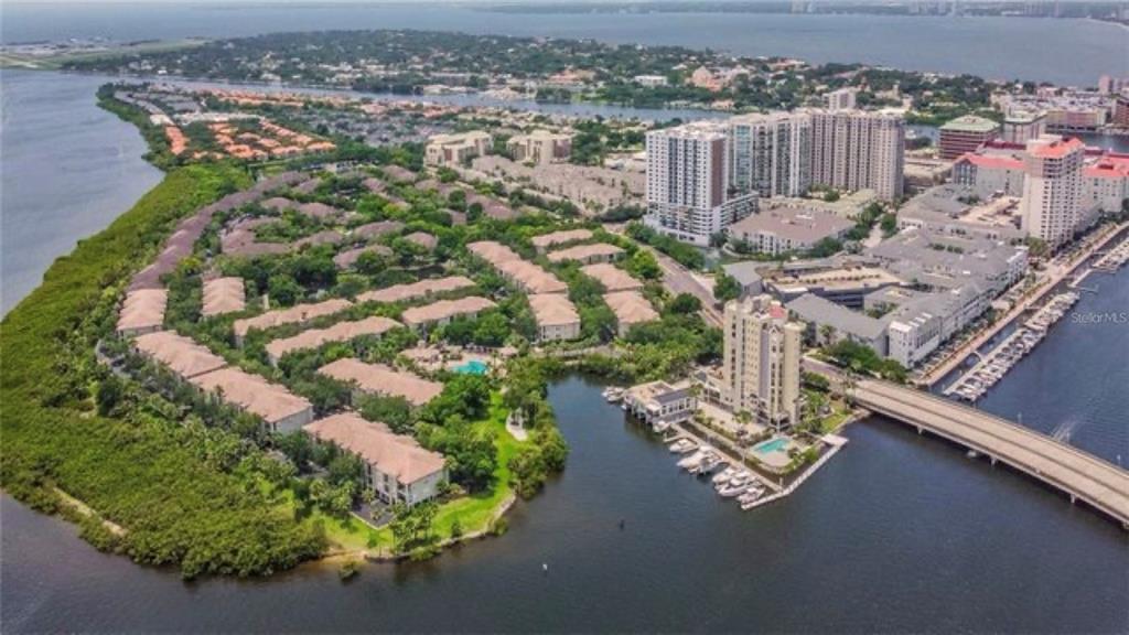 An aerial view shows a waterfront residential complex with multi-story buildings, a marina, and bridge — 716 PROMENADE PLACE, TAMPA, FL