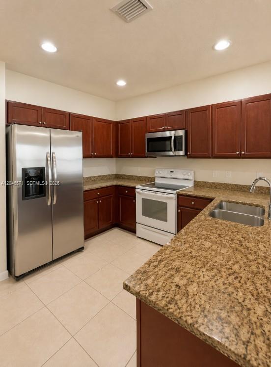 A kitchen features wood cabinets, granite countertops, stainless steel appliances, and light-colored tile flooring — 8879 SW 227th Ter, Cutler Bay FL 33190, CUTLER BAY, FL
