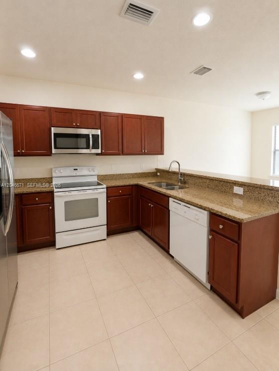 A kitchen features dark wood cabinets, granite countertops, and white appliances — 8879 SW 227th Ter, Cutler Bay FL 33190, CUTLER BAY, FL