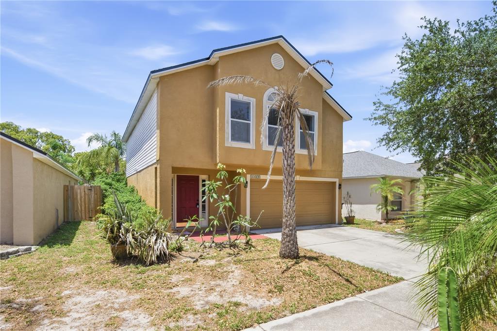 A two-story house with tan stucco siding, a red front door, and a two-car garage — 11535 IVY FLOWER LOOP, RIVERVIEW, FL