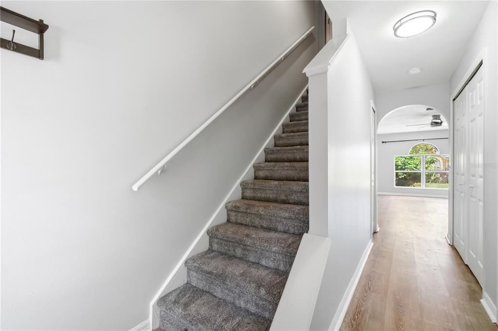 A carpeted staircase leads to an upper floor next to a hallway with wood flooring — 11535 IVY FLOWER LOOP, RIVERVIEW, FL