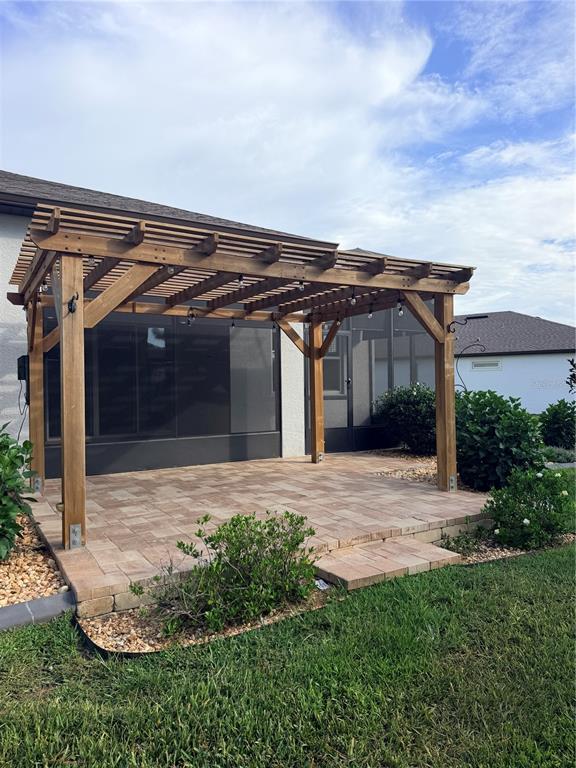 A wooden pergola stands over a paved patio next to a screened-in porch — 8975 SW 59TH LANE ROAD, OCALA, FL