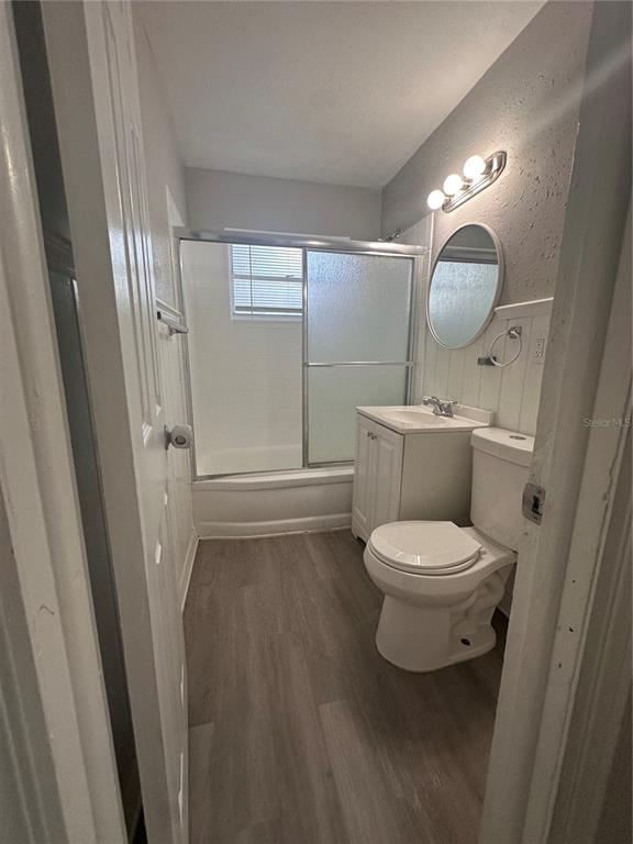 A bathroom features a tub-shower combination, a white vanity, a toilet, and wood-look flooring — 4017 WATSON ROAD, TAMPA, FL