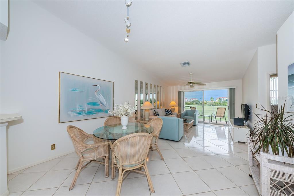 A dining area with a glass table and wicker chairs opens into a bright living room — 6151 BAHIA DEL MAR BOULEVARD UNIT 220, ST PETERSBURG, FL