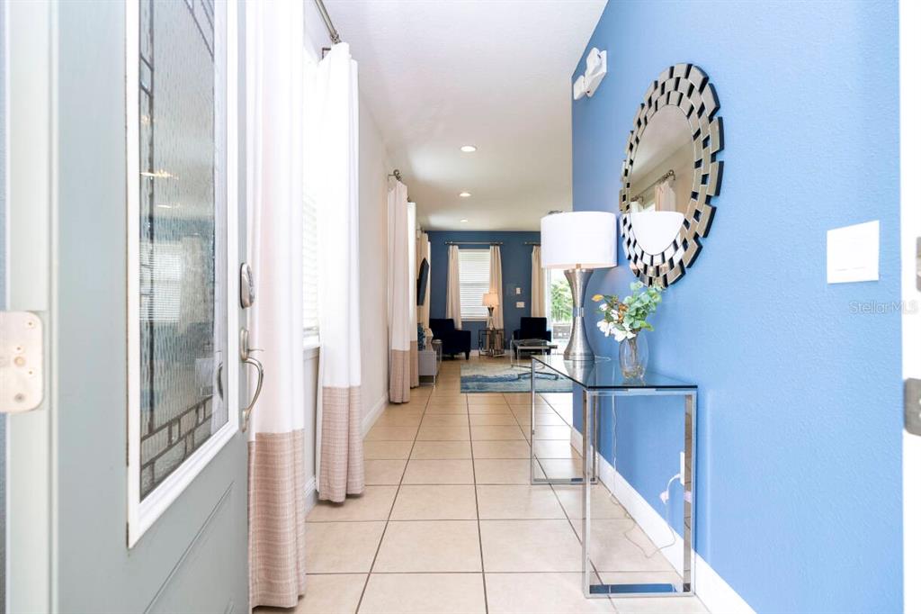 A tiled entryway leads into a living area with blue walls and a glass console table — 7479 MARKER AVENUE, KISSIMMEE, FL