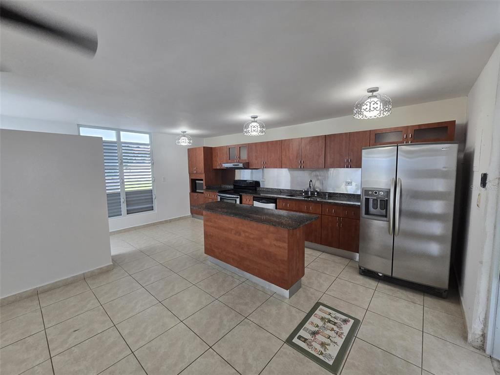 A kitchen features wood cabinets, a granite-topped island, stainless steel appliances, and tile flooring — AE-5 CALLE BARCELONA, HUMACAO, PR