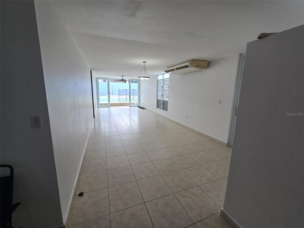 An empty room with light-colored tile flooring, white walls, and a sliding glass door — AE-5 CALLE BARCELONA, HUMACAO, PR
