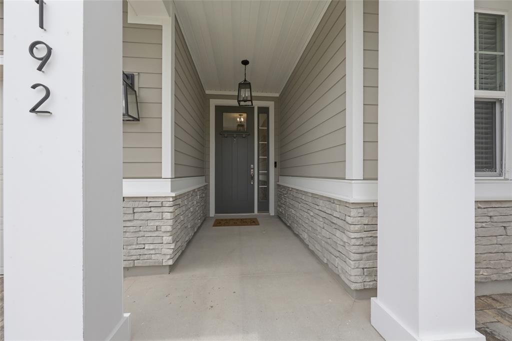 A covered front porch features a gray door, stone siding, and white pillars — 192 GOLDENROD DRIVE, ST AUGUSTINE, FL